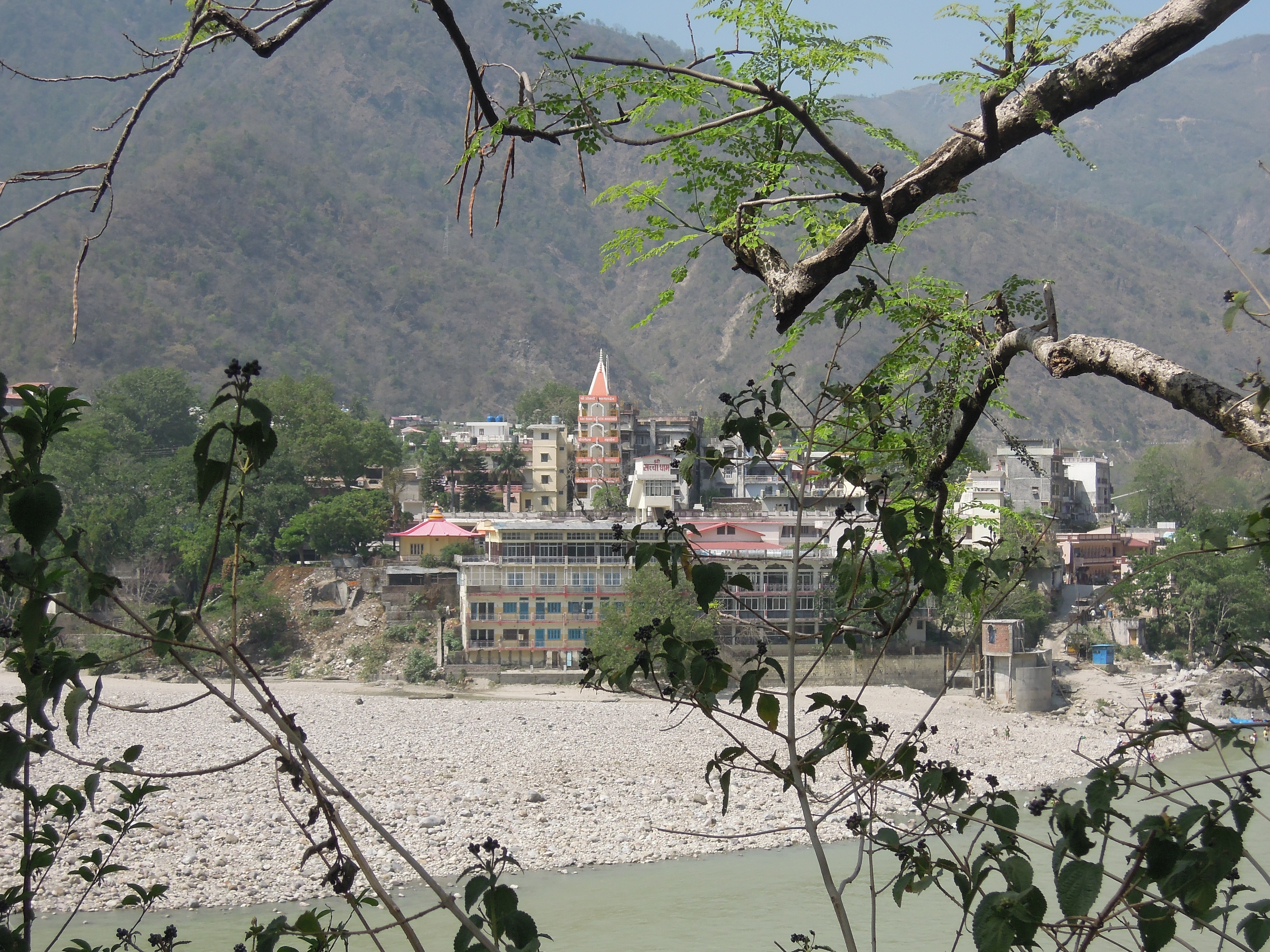 Rishikesh town by the Ganges River with hills in the background.