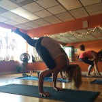 A woman performing a challenging yoga pose indoors on a mat.