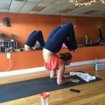 Person practicing advanced yoga pose in a mirrored studio.