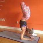 Woman practicing a forearm stand yoga pose indoors.