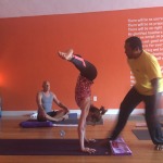 People practicing yoga indoors with bright orange walls.