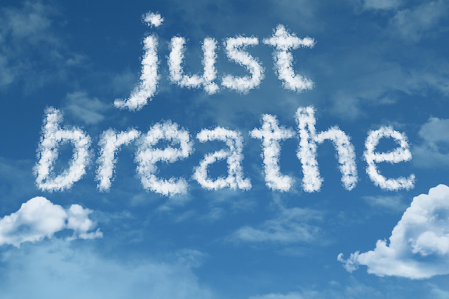 Skywriting in clouds spells 'just breathe' on a bright blue sky.