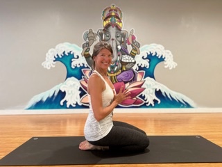 Woman practicing yoga in front of a colorful ocean wave mural.