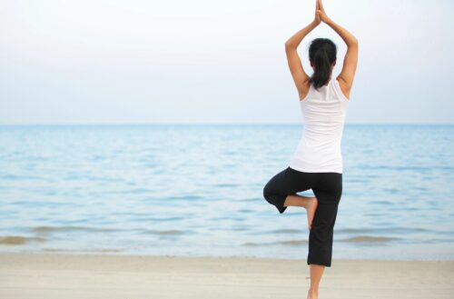 Woman practicing yoga on the beach at sunrise.