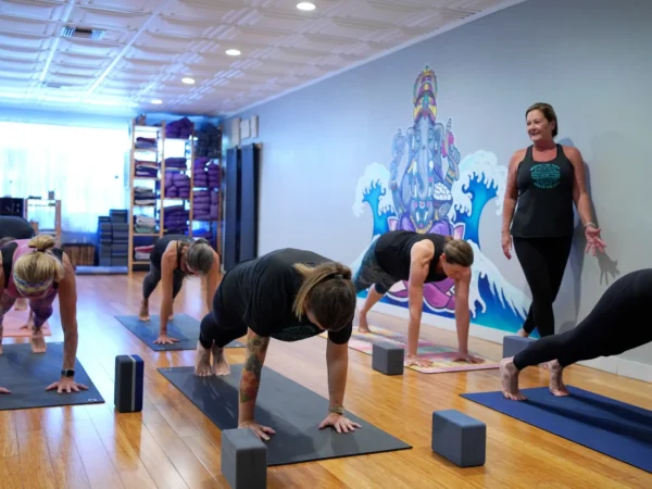 Group yoga class doing plank pose in studio